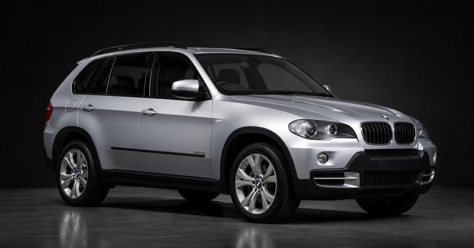 Silver BMW X5 (E70, 2nd gen) in a dark photographic studio