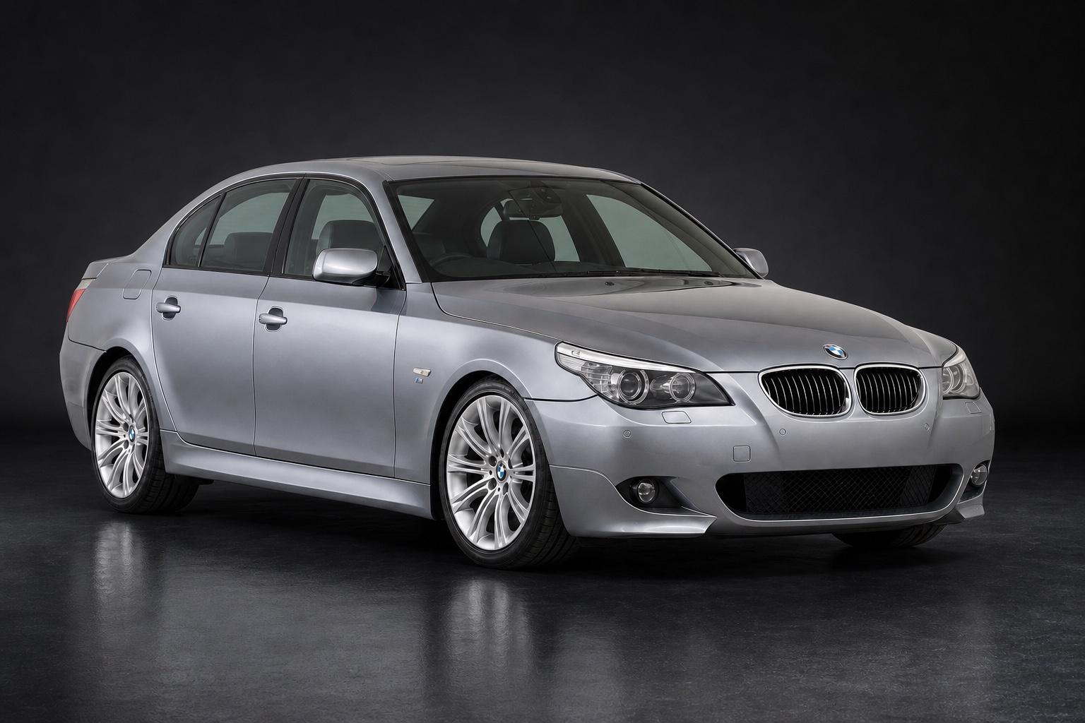 Medium metallic grey (reference-matched) BMW 530d M Sport (E60 facelift) in a dark photographic studio